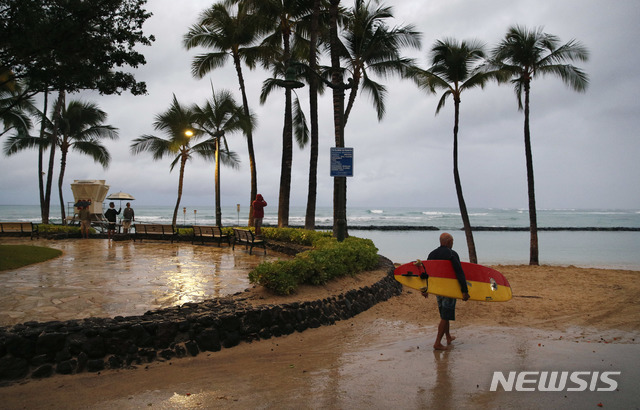 호놀룰루( 하와이)= AP/뉴시스】 허리케인 레인이 열대성 폭풍이 되어 물러간 25일(현지시간) 호놀룰루이 와이키키 해변에 가랑비가 내리는 가운데 한 서퍼가 바다로 걸어가고 있다.&nbsp;&nbsp; 