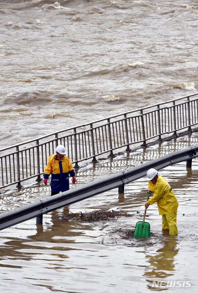 【대구=뉴시스】우종록 기자 = 많은 비가 내리며 대구에 호우경보가 내려진 27일 오전 대구 북구 대현동 칠성교 아래 신천동로에서 시설공단 관계자가 빗물에 떠내려온 나뭇가지를 제거하고 있다. 2018.08.27.&nbsp; wjr@newsis.com 