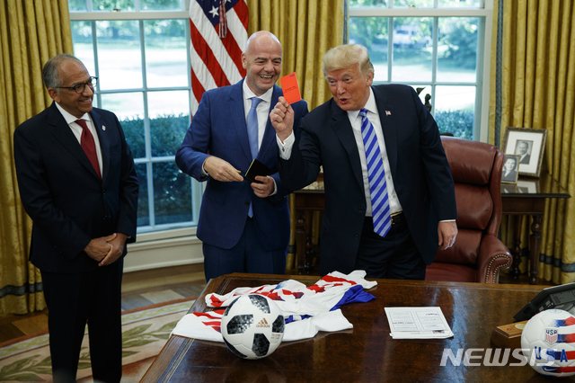 【워싱턴=AP/뉴시스】도널드 트럼프 미국 대통령이 28일(현지시간) 워싱턴 백악관 오벌오피스에서 지안니 인판티노 국제축구협회(FIFA) 회장(가운데)으로부터 받은 레드카드를 들어보이고 있다. 2018.08.29