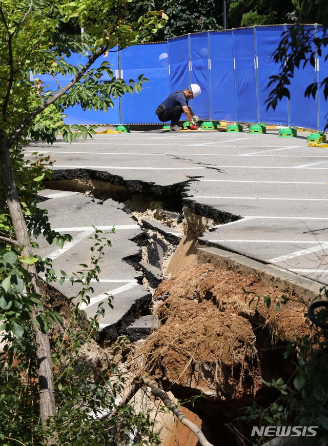 【서울=뉴시스】고범준 기자 = 31일 새벽 서울 금천구 가산동 한 아파트 인근 도로에서 싱크홀(땅꺼짐)이 발생해 아파트 주민 150여명이 긴급 대피했다.&nbsp; 소방당국은 최근 내린 강한 비로 인해 지반이 약해지면서 땅이 내려앉은 것으로 추정, 아파트 인근 공사장과 도로에서 가로 30ｍ, 세로 10ｍ, 깊이 6ｍ의 싱크홀이 발생한 것으로 보고 정확한 사고 원인을 조사하고 있다고 밝혔다.&nbsp; 사진은 이날 오후 현장 모습. 2018.08.31.&nbsp; bjko@newsis.com