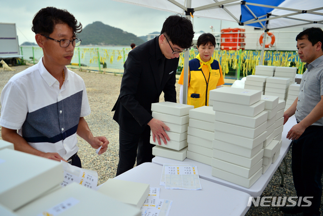 【진도=뉴시스】변재훈 기자 = 3일 오후 전남 진도군 임회면 팽목항에 설치됐던 세월호 참사 희생자 분향소가 철거되는 가운데 진도군청 직원들이 참사 희생자의 사진을 담을 종이상자를 준비하고 있다. 2018.09.03.&nbsp; wisdom21@newsis.com