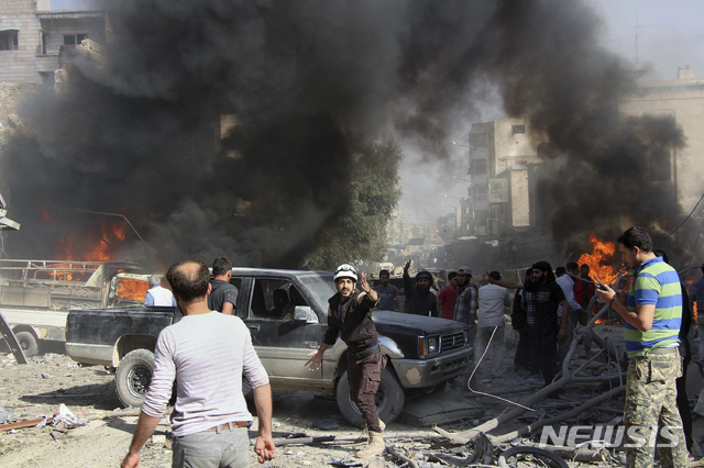 FILE - This file photo provided Sunday, Oct. 8, 2017 by the Syrian Civil Defense White Helmets, which has been authenticated based on its contents and other AP reporting, shows Civil Defense workers and Syrian citizens gathering after an airstrike hit a market in Maaret al-Numan in southern Idlib, Syria. When the presidents of Russia, Turkey and Iran meet in Tehran on Friday, Sept. 7, all eyes will be on their diplomacy averting a bloodbath in Idlib, Syria's crowded northwestern province and last opposition stronghold. The three leaders whose nations are all under U.S. sanctions have an interest in working together, but Idlib is complicated and they have little common ground. (Syrian Civil Defense White Helmets via AP, File)