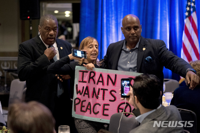 【워싱턴=AP/뉴시스】 존 볼턴 미국 백악관 국가안보보좌관이 10일(현지시간) 미국 워싱턴DC에서 열린 '연방주의자 협의회' 행사에 참석해 연설하기 직전 그의 외교 행보에 항의하는 기습시위가 벌어지고 있다. 여성평화단체 '코트핑크' 설립자인 메데이아 벤저민이 "이란은 평화를 원한다"는 문구를 적은 분홍색 손팻말을 들고 볼턴을 향해 "전쟁주의자(war hawk)"라고 외치다가 경호원들에게 끌려나가고 있다. 2018.9.11