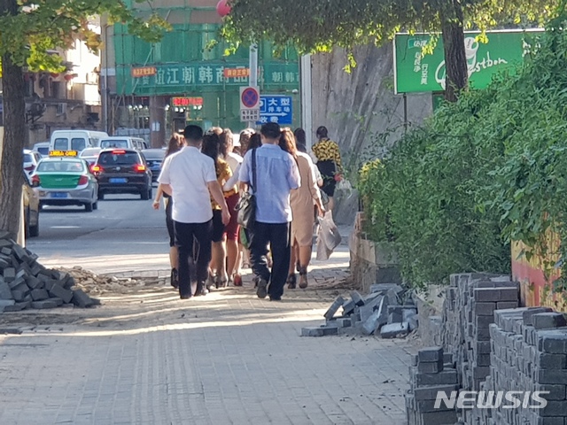 【단둥=뉴시스】김성진 기자 = 압록강변을 따라 출근중인 북한식당 종업원들. 약 30여명의 종업원이 관리자 3명의 인솔하에 압록강변을 따라 숙소까지 도보로 이동했다. 그들이 단체로 움직이지만 단둥 시민들은 크게 신경쓰지 않았다. 양쪽 모두 서로의 모습이 익숙한 듯 했다. 2018.09.16.ksj87@newsis.com