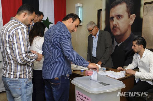 시리아 관영 사나 통신 제공으로, 16일  수도 다마스쿠스에서 시의회 선거 투표가 실시되고 있다. 아사드 대통령 사진이 보인다.  AP