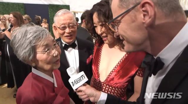 【서울=뉴시스】 한국계 할리우드 배우 샌드라 오의 어머니 오영남씨가 제70회 에미상 시상식 레드카펫에서 인터뷰에 응하고 있다. 뒤에 보이는 남성은 샌드라 오의 아버지 오준수씨. BBC는 18일(현지시간) 이 쇼의 스타가 된 것은 한복을 입고 등장한 샌드라 오의 어머니라고 평했고, 미국 대중전문 매체 버라이어티는 오씨와의 인터뷰 영상을 올리며 그에 주목했다. (사진=버라이어티 캡처) 2018.09.18