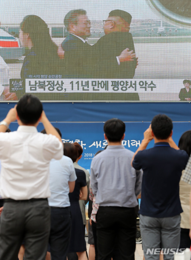 【서울=뉴시스】박주성 기자 = 18일 오전 서울 중구 서울광장에서 제3차 남북정상회담을 위해 평양에 도착한 문재인 대통령을 영접하는 김정은 북한 국무위원장이 포옹하는 TV중계를 시민들이 지켜보고 있다. 2018.09.18. park7691@newsis.com