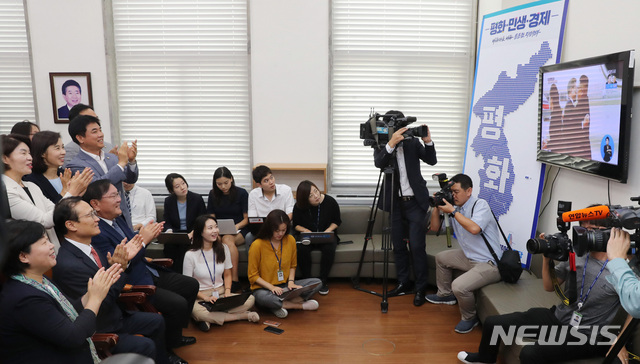 【서울=뉴시스】이종철 기자 = 18일 오전 서울 여의도 국회에서 열린 더불어민주당 원내대책회의에 앞서 홍영표 원내대표를 비롯한 의원들이 남북정상회담을 위해 평양 순안공항에 도착한 문재인 대통령이 김정은 위원장을 만나는 모습을 방송으로 시청하고 있다. 2018.09.18.jc4321@newsis.com