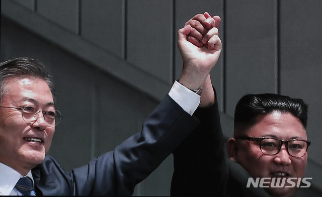 【남북정상회담 프레스센터(서울)=뉴시스】최진석 기자 = 남북정상회담 둘째날인 19일 평양 능라도 5.1경기장에서 문재인 대통령이 평양 시민들을 상대로 연설을 마친 뒤 김정은 북한 국무위원장과 손을 잡은 모습이 서울 중구 동대문디자인플라자(DDP)에 차려진 남북정상회담 평양 서울 프레스센터에 중계되고 있다. 이날 문 대통령은 대한민국 대통령으로는 처음으로 북한 주민 상대로 연설을 했다. 2018.09.19.myjs@newsis.com