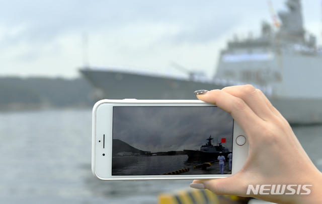 【창원=뉴시스】차용현 기자 = 20일 오전 서아프리카 가나해역에서 우리나라 및 외국선박의 호송작전 등을 무사히 수행하고 경남 창원시 진해군항으로 귀항하는 청해부대 26진 대원들의 가족들이 입항하는 문무대왕함을 스마트폰에 담고 있다. 2018.09.20. con@newsis.com