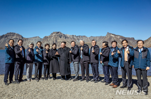 【백두산=뉴시스】평양사진공동취재단 박진희 기자 = 20일 백두산 천지에서 김정은 위원장 내외가 남쪽 수행원들과 기념사진을 찍고 있다. 처음에는 손을 내리고 있었으나, 강경화 외교부 장관으로부터 "남쪽에서 유행하는 손가락 하트를 해보자"는 제안을 받고, 따라하고 있다. 리설주 여사는 김 위원장의 손을 받치고 있다. 2018.09.23. (사진=청와대 제공) photo@newsis.com