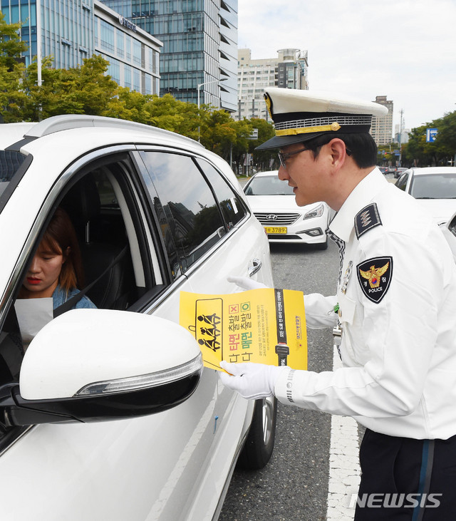 【대전=뉴시스】 함형서 기자= 전좌석 안전벨트 착용 의무화가 시행되는 28일 오전 대전 서구 둔산동 정부청사역네거리에서 둔산경찰서 경찰관들이 시민들에게 팜플렛을 나눠주며 계도활동을 하고 있다. 2018.09.28.foodwork23@newsis.com
