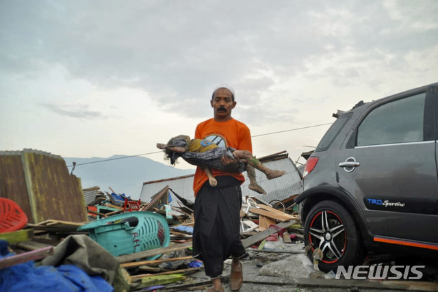 In this Saturday, Sept. 29, 2018, file photo, a man carries the body of a child who was killed in the tsunami in Palu, Central Sulawesi, Indonesia. (AP Photo/Rifki, FIle)