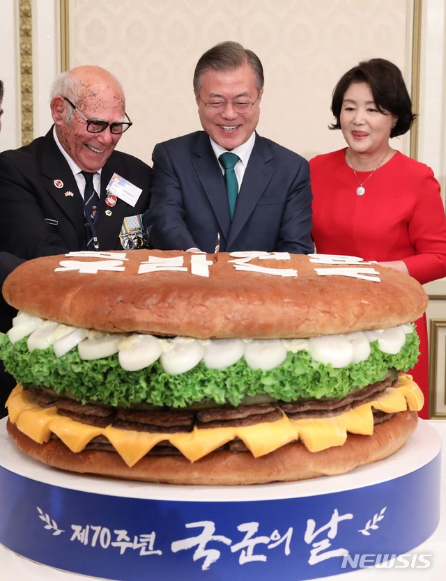 【서울=뉴시스】전신 기자 = 문재인 대통령이 1일 청와대 영빈관에서 열린 제70주년 국군의 날 경축연에서 대형 햄버거를 자르고 있다. 왼쪽부터 유엔군 참전 용사인 혹스워스 영국 예비역 육군하사, 문 대통령, 김정숙 여사. 2018.10.01.&nbsp; photo1006@newsis.com