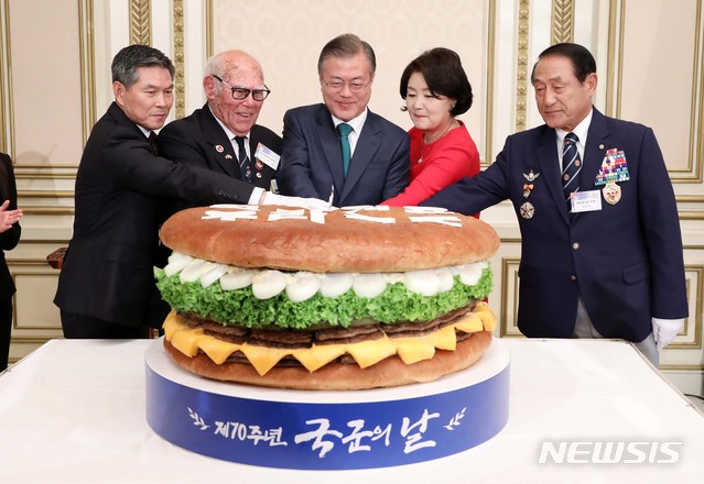 【서울=뉴시스】전신 기자 = 문재인 대통령이 1일 청와대 영빈관에서 열린 제70주년 국군의 날 경축연에서 대형 햄버거를 자르고 있다. 왼쪽부터 정경두 국방부 장관, 유엔군 참전 용사인 혹스워스 영국 예비역 육군하사, 문 대통령, 김정숙 여사, 김진호 재향군인회장. 2018.10.01.&nbsp; photo1006@newsis.com