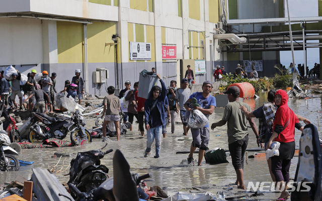 【팔루(인도네시아)=AP/뉴시스】강진과 쓰나미가 덮쳐 식량과 식수 등 생필품이 크게 부족해진 인도네시아 술라웨시주 팔루에서 지난달 30일 주민들이 한 쇼핑몰에서 물건들을 약탈해 나오고 있다. 상점들을 보호해야 하는 경찰이 약탈자들을 향해 경고 사격 및 최루가스를 발사하기도 해 팔루에 긴장이 고조되고 있다. 2018.10.2