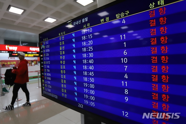 【제주=뉴시스】조수진 기자 = 5일 윈드시어경보와 태풍경보가 내려진 제주국제공항을 오가는 항공편이 오후 6시부터 전편 결항됐다. 한 공항 이용객이 결항 일정으로 가득 채워진 제주공항 입국장에 설치된 운항 스케쥴 모니터를 지나고 있다. 2018.10.05.&nbsp; susie@newsis.com
