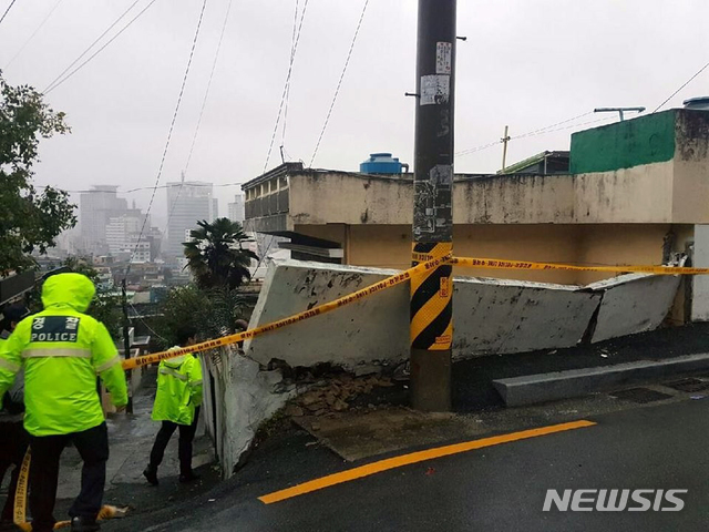 【부산=뉴시스】 하경민 기자 = 태풍경보가 발효된 6일 부산 부산진구의 한 다가구주택의 지반이 무너지는 바람에 높이 1m, 길이 7m 상당의 담장이 붕괴되는 사고가 났다. 2018.10.06. (사진=부산경찰청 제공)yulnetphoto@newsis.com