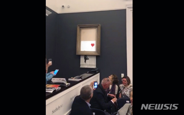 【런던=AP/뉴시스】영국 런던 소더비 경매장에서 5일(현지시간) 뱅크시의 '풍선을 든 소녀'가 104만파운드에 낙찰된 직후 갑자기 액자에서 그림이 미끌어 떨어지더니 분쇄되고 있다. 사진은 동영상을 캡처한 것이다. 2018.10.18