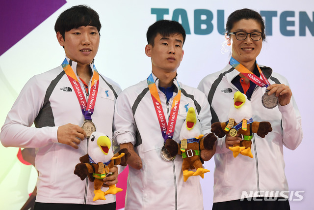 【자카르타(인도네시아)=뉴시스】 사진공동취재단 = 남북 탁구단일팀 '코리아'가 장애인 체육 사상 최초로 은메달을 목에 걸었다. 13일 오전(현지시간) 인도네시아 자카르타 에코벤션 안촐에서 열린 '2018 인도네시아 장애인아시아경기대회' 남자 탁구 단체전(장애등급 TT6-7) 시상식에서 (오른쪽부터)남측 박홍규,북측 김영록, 남측 이세호 선수가 메달을 들고 기념사진을 촬영하고 있다. 2018.10.13. photo@newsis.com