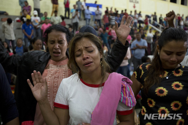 Honduran migrants pray at an improvised shelter in Chiquimula, Guatemala, Tuesday, Oct. 16, 2018. U.S. President Donald Trump threatened on Tuesday to cut aid to Honduras if it doesn't stop the impromptu caravan of migrants, but it remains unclear if governments in the region can summon the political will to physically halt the determined border-crossers. (AP Photo/Moises Castillo)