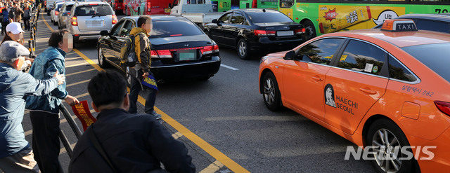 【서울=뉴시스】박주성 기자 = 카카오 카풀 서비스에 반발하는 전국 택시업계가 파업에 돌입한 18일 오후 서울 광화문광장에서 열린 택시 생존권 사수 결의대회를 마친 후 청와대로 행진하던 참가자가 운행 중인 택시에 다가가 항의하고 있다. 2018.10.18. park7691@newsis.com
