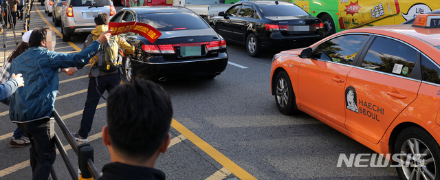 【서울=뉴시스】박주성 기자 = 카카오 카풀 서비스에 반발하는 전국 택시업계가 파업에 돌입한 18일 오후 서울 광화문광장에서 열린 택시 생존권 사수 결의대회를 마친 후 청와대로 행진하던 참가자가 운행중인 택시에 다가가 항의하고 있다. 전국 택시업계의 파업은 18일 새벽 네시부터 19일 새벽 네시까지 하루 동안 계속될 예정이다. 2018.10.18. park7691@newsis.com