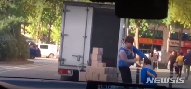 【서울=뉴시스】서울 마포구 공덕오거리에서 CJ대한통운 유니폼을 입은 택배기사가 지적장애가 있는 것으로 보이는 동료를 폭행하는 장면이 담긴 영상이 확산해 논란이 되고 있다. 경찰 확인 결과 이들은 형제 사이로 밝혀졌다. <사진: 영상 캡처> 2018.10.19