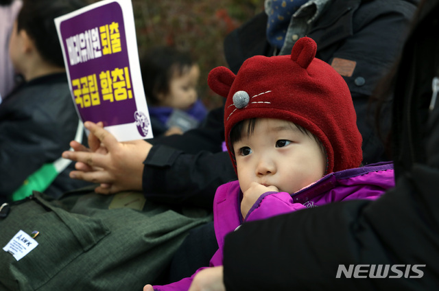 【서울=뉴시스】조성봉 기자 =  20일 오전 서울 중구 시청역 4번 출구 앞에서 열린 '유아교육, 보육 정상화를 위한 모두의 집회'에서 한 어린이가 엄마 무릎에 앉아 간식을 먹고 있다. 시민단체 '정치하는엄마들' 주최로 열린 이날 집회에서 참가자들은 최근 사회적 공분을 산 비리 유치원 사태와 관련해 한국유치원총연합회와 교육 당국 책임자 처벌, 국가회계시스템 에듀파인 도입, 국공립 단설 유치원 확충을 정부에 촉구했다.2018.10.20.suncho21@newsis.com