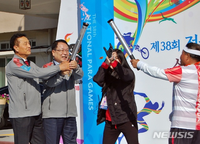 【익산=뉴시스】강명수 기자 = 제38회 전국장애인체육대회를 밝히기 위해 전북 익산시 금마면 미륵사지에서 채화된 성화가 체전 개막일인 25일 익산시청에서 정헌율(가운데) 시장과 조규대 시의장에 의해 점화돼 봉송주자에게 전달되고 있다. 2018.10.25.  smister@newsis.com