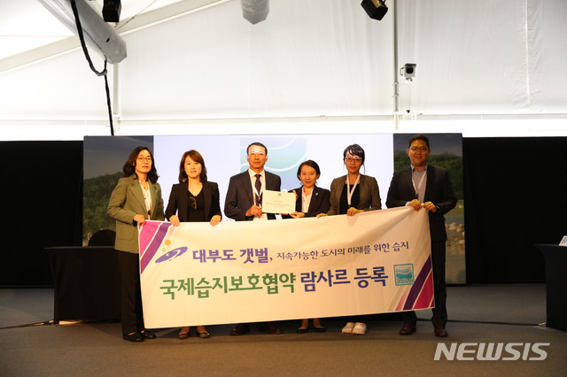 【안산=뉴시스】 조성필 기자 = 아랍에미리트 두바이에서 지난 25일 개최된 '제13차 람사르 협약 총회'에서 경기 안산시 대부도 갯벌이 람사르 습지로 공식 등록된 뒤 시관계자 등이 기념촬영을 하고 있다. 2018.10.26 (사진=안산시 제공) photo@newsis.com