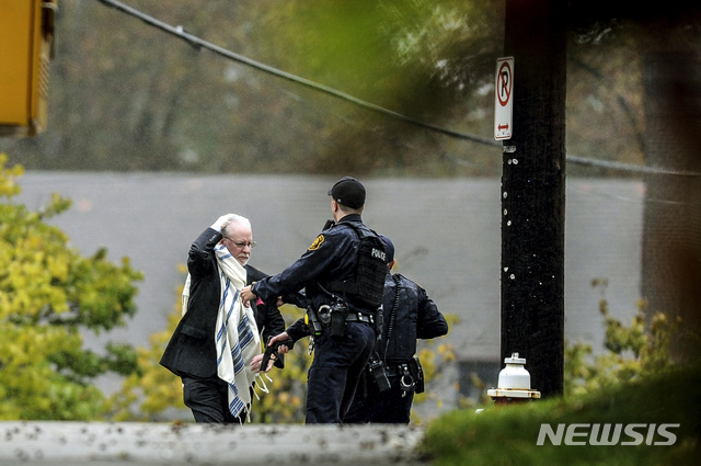 A man holds his head as he is escorted out of the Tree of Life Congregation by police following a shooting at the Pittsburg synagogue, Saturday, Oct. 27, 2018. (Alexandra Wimley/Pittsburgh Post-Gazette via AP)