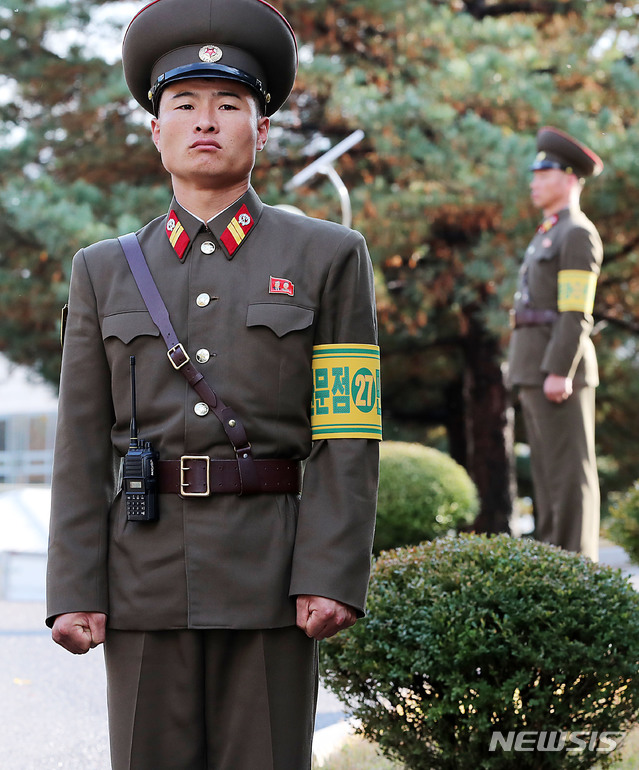 【판문점=뉴시스】사진공동취재단 = 지난 25일 오후 1시 판문점 공동 경비구역(JSA) 안 모든 화기와 탄약 초소를 철수했다. 26일 북측 판문점 뒷편 통일각에서 노랑색 바탕에 녹색으로 적힌 '판문점 민사경찰 27'이라는 완장을 찬 채 북한 군인이 경비를 서고 있다. 2018.10.28. photo@newsis.com