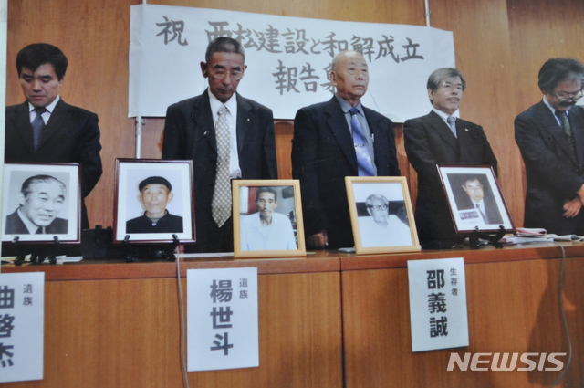 【서울=뉴시스】중국인 징용 피해자들이 2009년 11월 일본 기업 니시마츠건설 측과 사과 및 배상 방안에 합의한 뒤 '화해성립 보고집회'를 갖는 모습. 단상 위에 놓인 액자 속 인물들은 피해자 중 이미 사망한 이들이다. 뉴시스 자료사진.