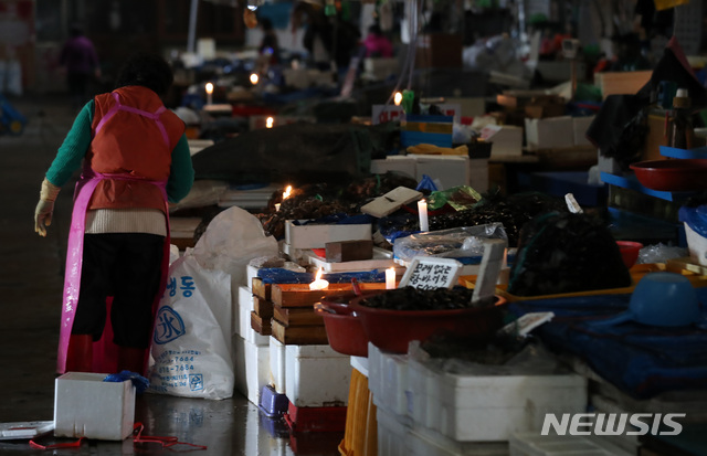 【서울=뉴시스】이영환 기자 = 수협이 노량진 수산시장 구시장 전역에 단전과 단수를 진행한 지 하루 지난 6일 오전 서울 동작구 노량진 수산시장 구시장이 어둑어둑한 가운데 상인들이 촛불을 켜고 장사를 하고 있다. 2018.11.06.&nbsp; 20hwan@newsis.com
