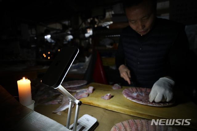 【서울=뉴시스】박미소 기자 = 6일 서울 동작구 구 노량진 시장이 단전된 상황에서 차모씨(57)가 휴대용 전구 불빛에 의지해 회를 뜨고 있다. 차씨는 "촛불로는 작업에 한계가 있어 급하게 휴대용 전구를 구입했다"고 밝혔다. 2018.11.06.&nbsp; misocamera@newsis.com