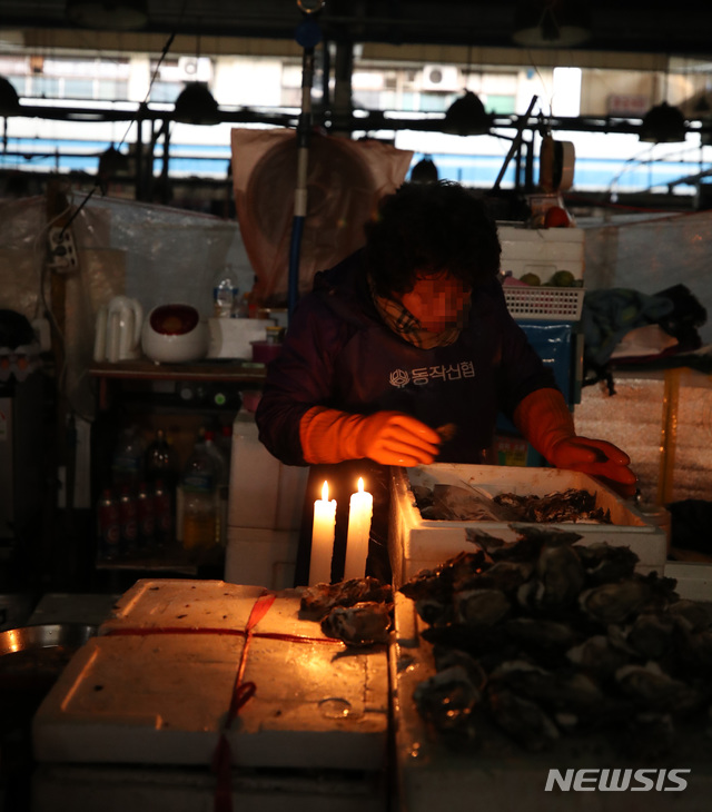 【서울=뉴시스】박미소 기자 = 6일 서울 동작구 구 노량진 시장이 단전된 상황에서 한 상인이 촛불 아래에서 일을 하고 있다. 2018.11.06. misocamera@newsis.com