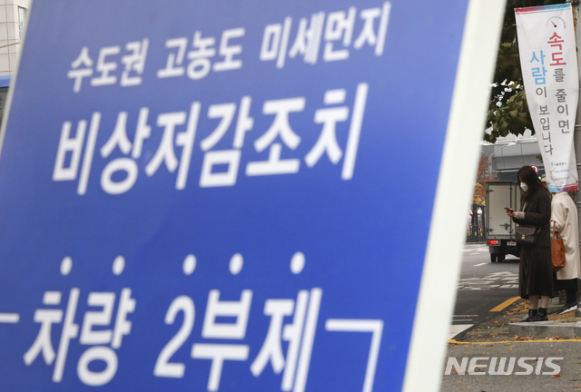 【서울=뉴시스】최진석 기자 = 서울을 비롯한 수도권에 '미세먼지 비상저감조치'가 발령된 7일 오전 서울 도로에 차량 2부제 안내 표지판 뒤로 한 시민이 마스크를 쓰고 있다. 2018.11.07.myjs@newsis.com