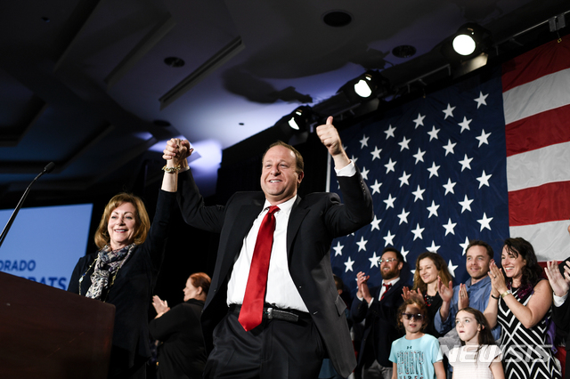【덴버=AP/뉴시스】재러드 폴리스 콜로라도 주지사 당선인이 6일(현지시간) 선거 결과가 확정된 후 덴버에서 지지자들을 환호에 답하고 있다. 옆의 여성은 부주지사 당선인 다이앤 프리마이다. 2018.11.7.
