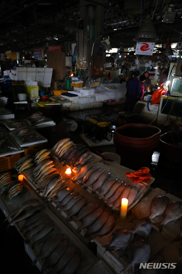 【서울=뉴시스】배훈식 기자 = 노량진 구(舊) 수산시장 철거가 시작되는 9일 오전 서울 동작구 구 시장에서 한 상인이 촛불을 켠 채 영업을 하고 있다. 수협중앙회는 이날 오후 5시까지 신 시장 이전 신청을 접수한 뒤 철거에 들어가겠다며 최후통첩을 한 상황이다. 2018.11.09. dahora83@newsis.com
