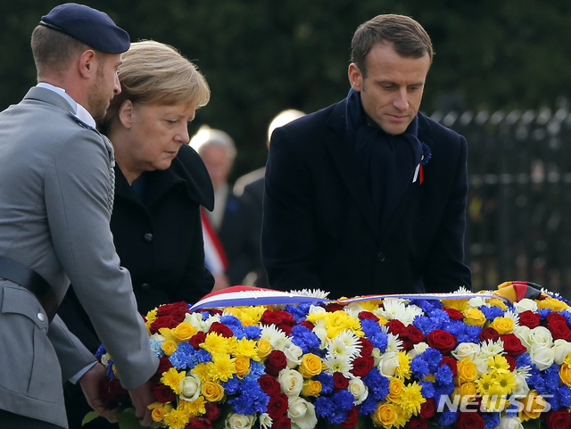 【콩피에뉴(프랑스)=AP/뉴시스】에마뉘엘 마크롱 프랑스 대통령과 앙겔라 메르켈 독일 총리가 10일 프랑스 파리 북부 콩피에뉴에서 1차 세계대전 종전 100주년을 기리는 행사 도중 화환을 공동 헌화하고 있다. 100년 전 격렬한 전투를 벌인 두 정상은 이날 우호 과시를 통해 변화된 양국 관계를 보여주었다. 이는 앞서 마크롱과 도널드 트럼프 미 대통령 간 거북한 만남과 대조를 이뤘다. 2018.11.11