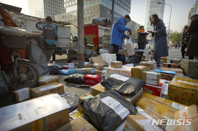 【베이징=AP/뉴시스】12일 중국 베이징 도심 건물 앞에서 사람들이 사설 택배업체 직원들으로부터 자신의 소포를 받고 있다. 중국 우정당국은 중국판 블랙프라이데이로 불리는 광군제(光棍節·독신자의 날) 11일 하루 주요 전자상거래 기업들의 택배주문건수가 13억5200만건에 달한다고 밝혔다. 2018.11.12 