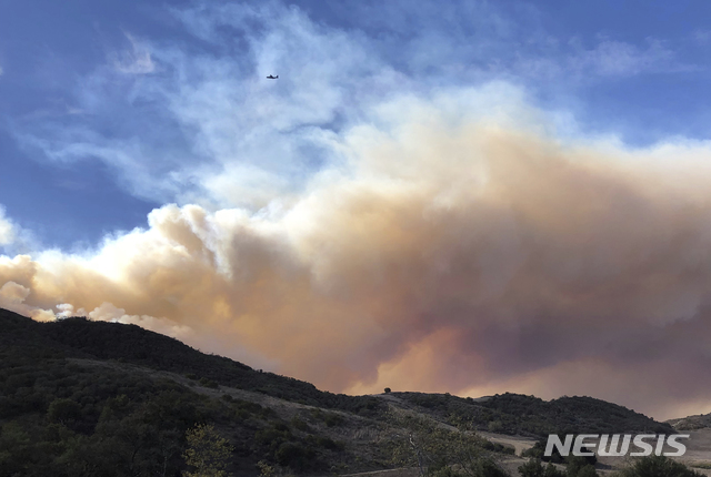 【AP/뉴시스】캘리포니아 남부 샌타 애나 산불지역 상공을 날고 있는 소방 헬리콥터(위쪽)가 점처럼 조그맣게 보인다.&nbsp; 