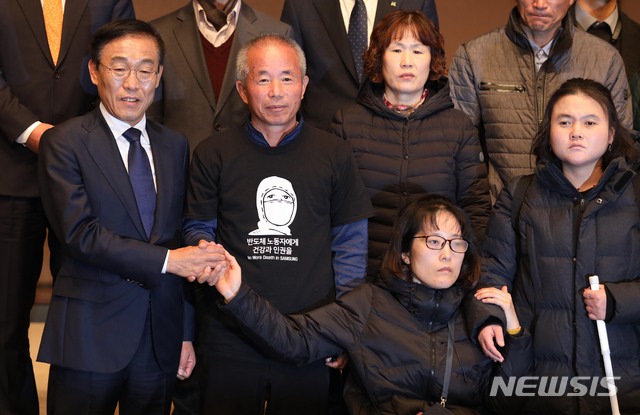 【서울=뉴시스】조성봉 기자 = 23일 오전 서울 중구 프레스센터 국제회의장에서 열린 삼성전자-반올림 중재 판정 이행 협의 협약식에서 김기남(왼쪽) 삼성전자 대표이사 반올림 황상기 대표를 비롯한 피해자들과 손을 잡고 있다. 2018.11.23. suncho21@newsis.com