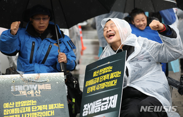 【서울=뉴시스】김진아 기자 = 전국장애인차별철폐연대 등 관계자들이 3일 서울 여의도 국회 앞에서 26번째 세계장애인의 날 장애등급제 ‘진짜’ 폐지 투쟁결의대회를 하고 있다.  이들은 장애인연금 대상 중증(3급) 확대, 개인·유형별 맞춤형 다양한 서비스 확대 및 예산 보장, 장애인 활동지원 24시간 보장 등을 요구했다. 2018.12.03.  bluesoda@newsis.com