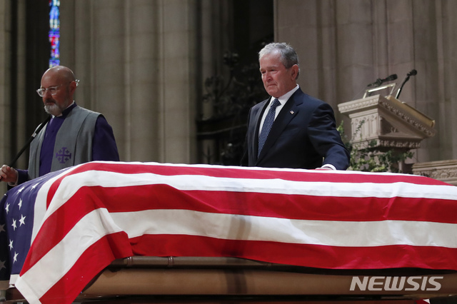 【워싱턴D.C.=AP/뉴시스】5일(현지시간) 미국 워싱턴D.C. 국립대성당에서 거행된 조지 H.W. 부시 전 미 대통령의 장례식에서 장남인 조지 W.부시 전 대통령이 슬픔을 억누르는 듯한 표정으로 성조기가 고이 덮힌 아버지의 관을 어루만지고 있다. 2018.12.06.