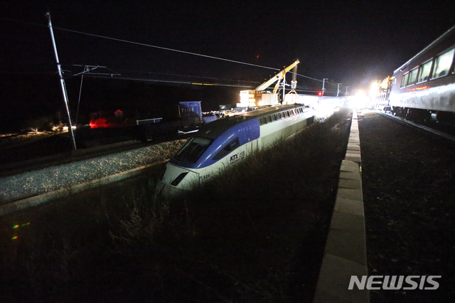 【강릉=뉴시스】김경목 기자 = 9일 오전 4시31분 코레일(한국철도공사) 관계자들이 강원도 강릉시 운산동 KTX 강릉선 남강릉 신호장 21호 지점에서 전날 오전 7시33분에 탈선한 서울행 KTX산천 제806열차의 2호 객차를 기중기로 들어올려 가대차(바퀴 기능)로 옮기고 있는 가운데 객차를 끌고 가는 기관차가 파손이 매우 심각해 가대차에 올리는 게 어려워지자 복선 선로 가운데 움푹 파인 맨땅에 옮겨져 있다. 기관차와 마찬가지로 90도로 꺽인 상태로 맞은편 선로까지 탈선한 1호 객차는 KTX산천용 가대차에 올려져 사고 현장 코앞에 위치한 강릉기지창으로 옮겨졌다. 2018.12.09. photo31@newsis.com?