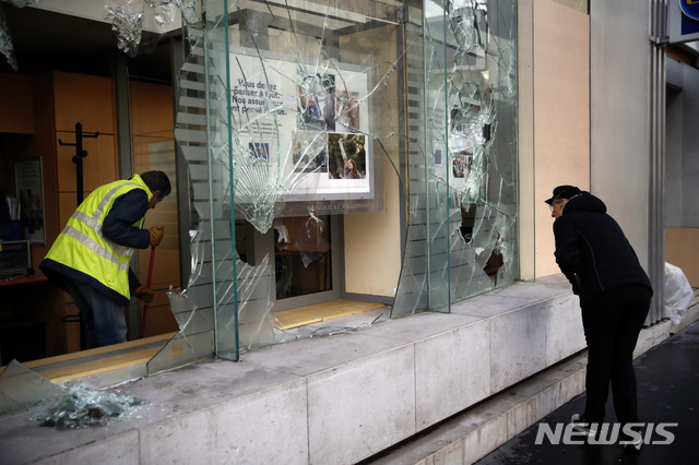 【파리=AP/뉴시스】 9일(현지시간) 프랑스 파리의 한 은행 앞에서 청소부와 시민들이 대규모 시위로 인해 깨진 유리창을 치우고 있다. 2018.12.10.