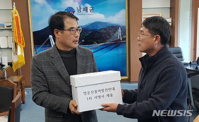 【남해=뉴시스】차용현 기자 = 경남 남해군 망운산 정상에 추진되고 있는 풍력발전소를 반대하는 범군민 반대대책위 김동수 위원장이 18일 오후 남해군청 군수실을 찾아 장충남 군수(왼쪽)에게 풍력발전소반대 1차 서명서를 제출하고 있다. 2018.12.18. con@newsis.com