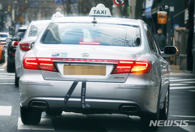 【서울=뉴시스】조성봉 기자 = 18일 오후 서울 도심의 택시들이 카카오모빌리티의 카풀앱 정식 서비스에 반대하며 국회의사당 앞에서 분신한 택시기사 최모 씨를 추모하는 근조리본을 차량 뒤에 달고 운행을 하고 있다. 2018.12.18.suncho21@newsis.com